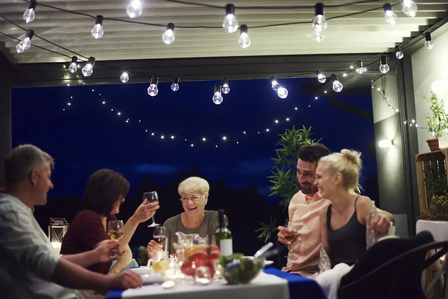Group of people enjoying a meal together at an outdoor table in the evening